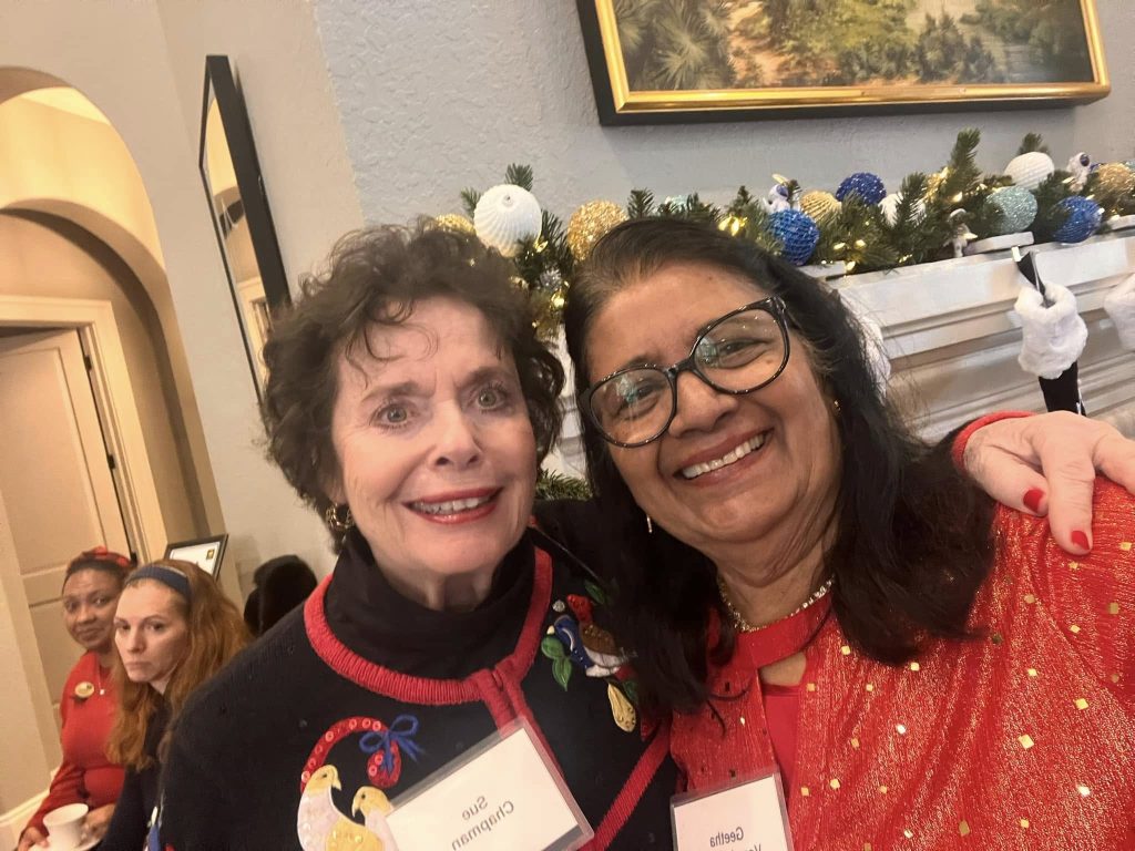 Two women smiling in front of a festive mantle with holiday decorations.