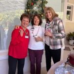 A group of women standing in front of a christmas tree.
